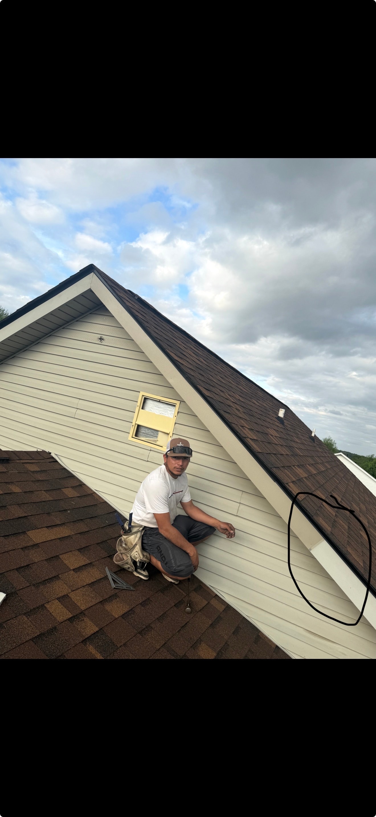 Roofer crouching on completed shingle roof