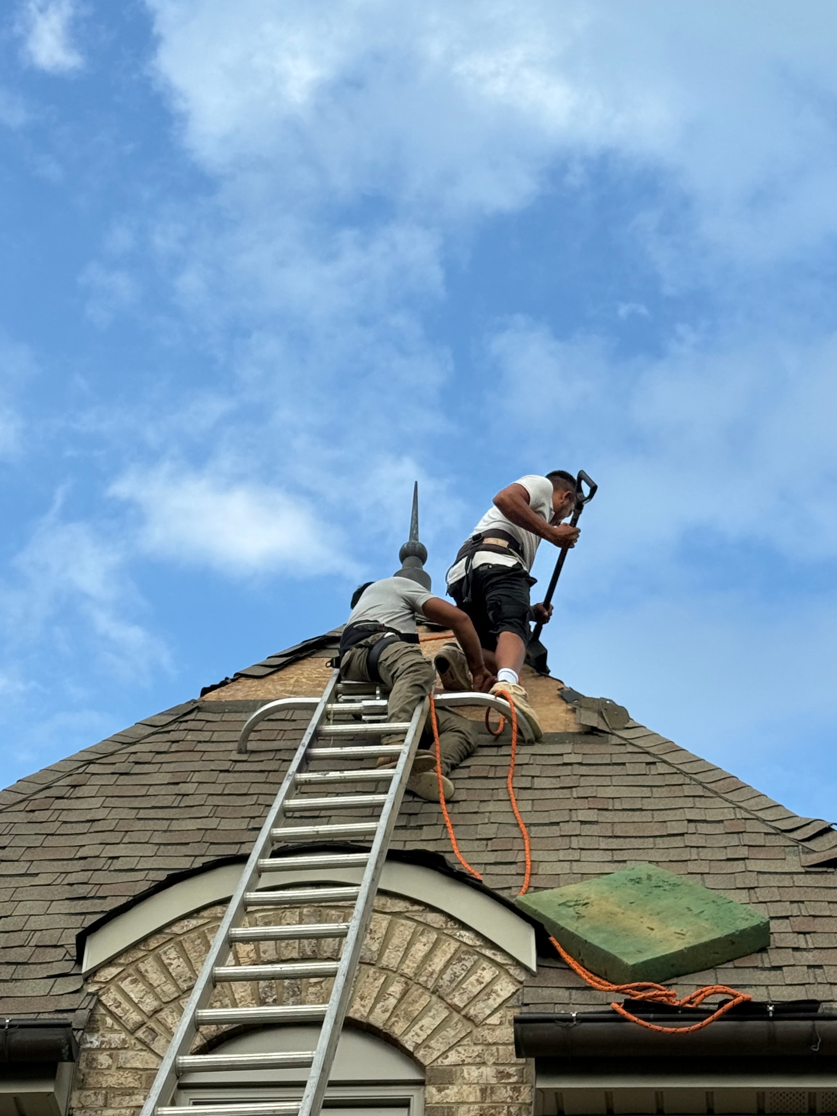 Worker on ladder during roof tear-off