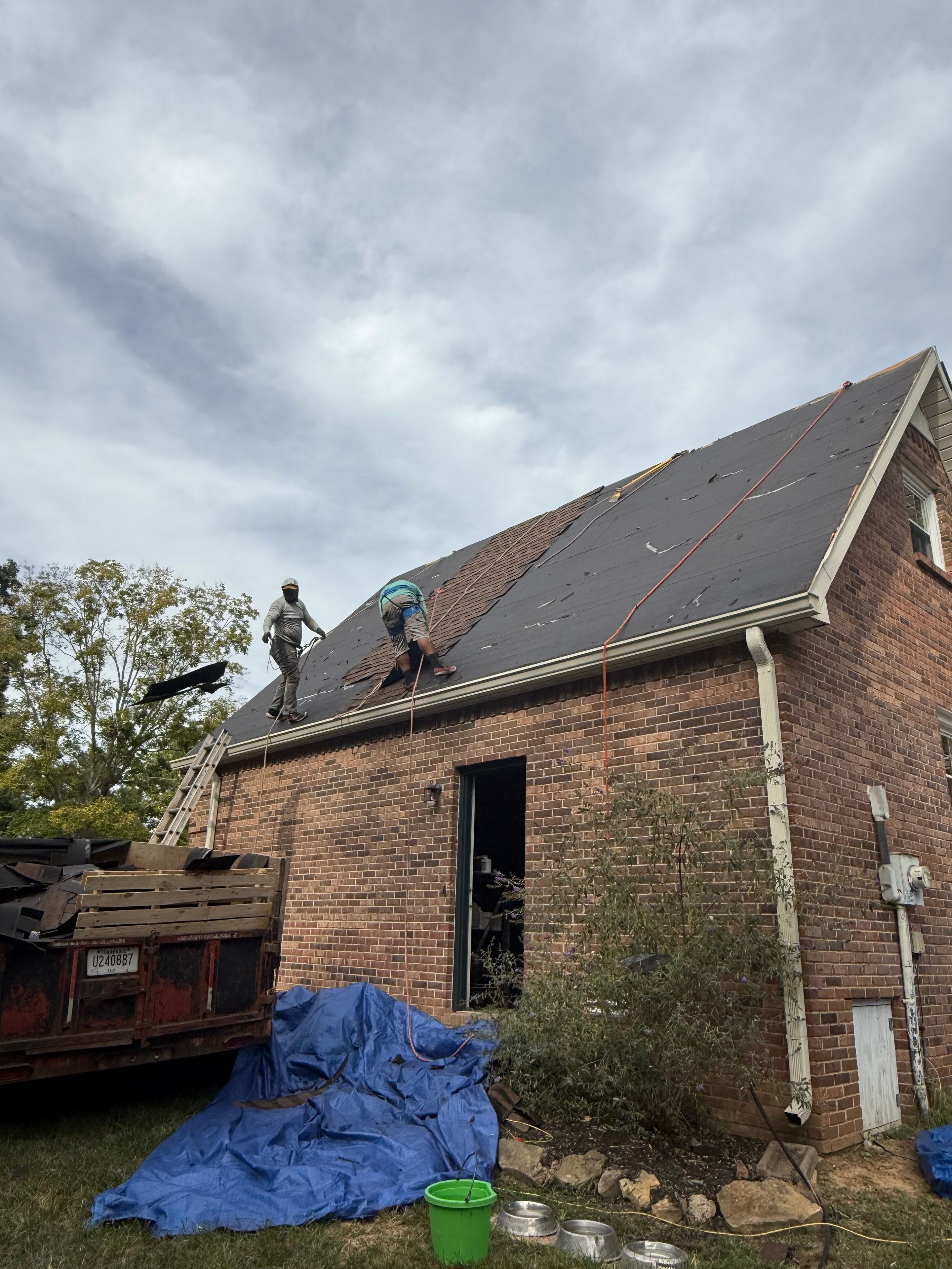 Crew removing old shingles from brick home