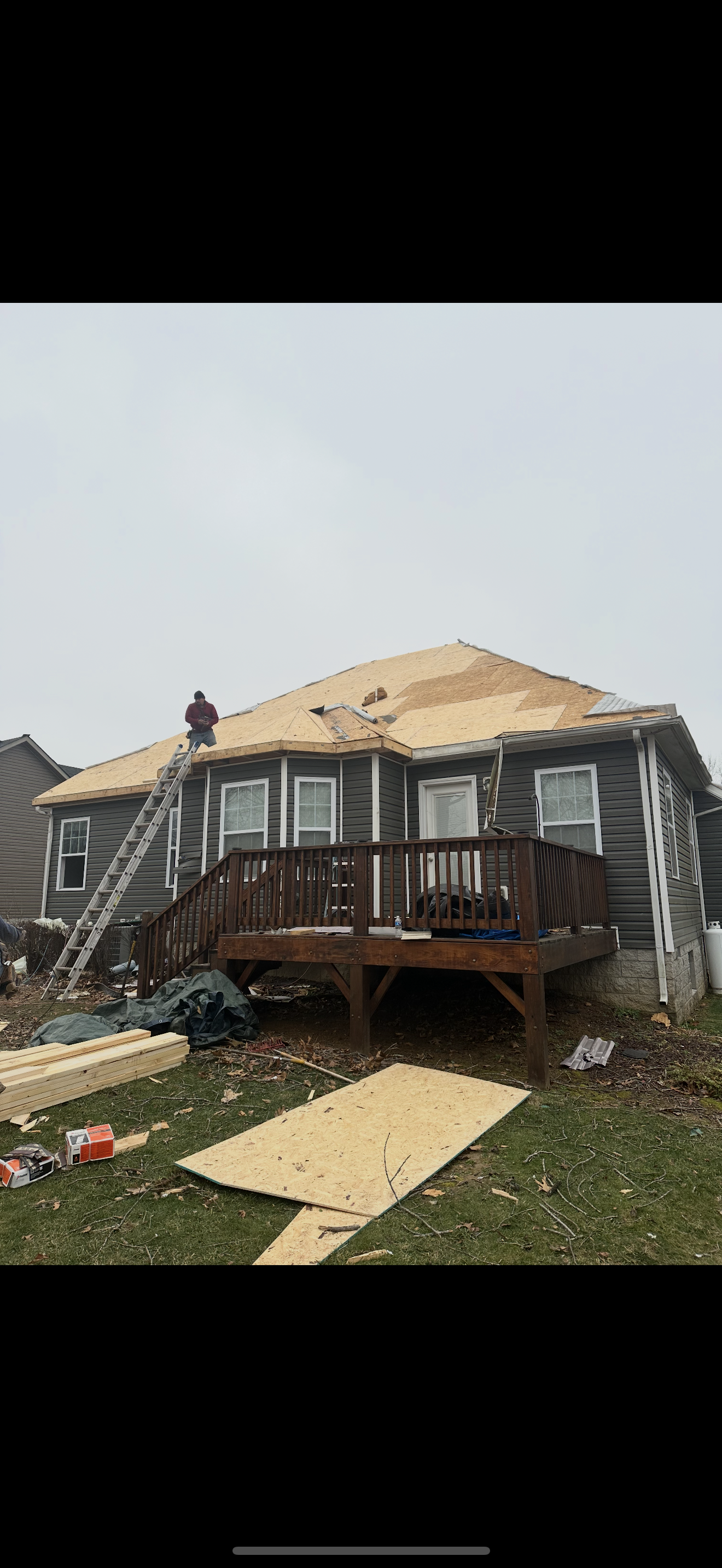 Roofer on ladder during roof decking installation