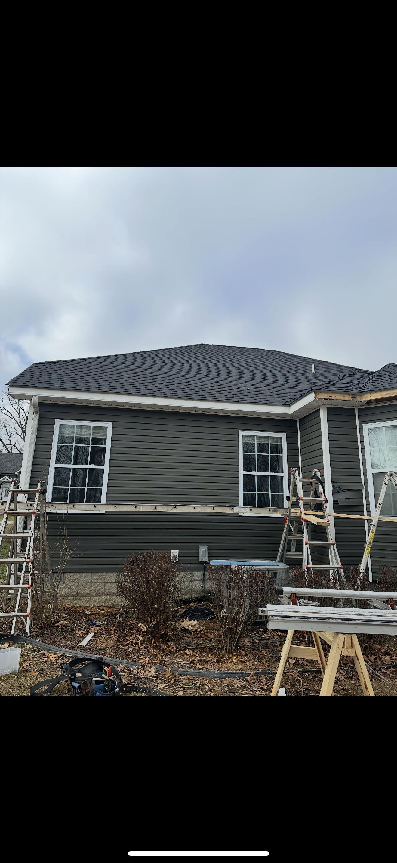 Completed dark shingle roof on gray siding home