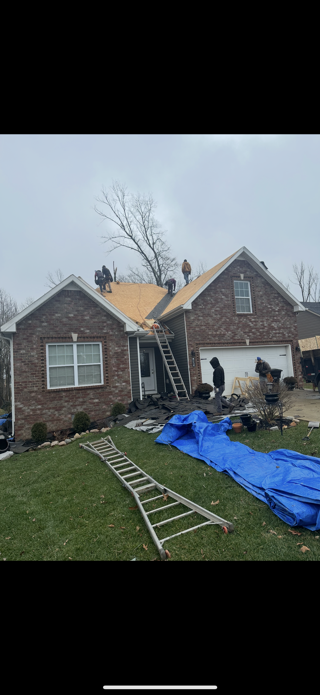Full crew working on brick home roof replacement