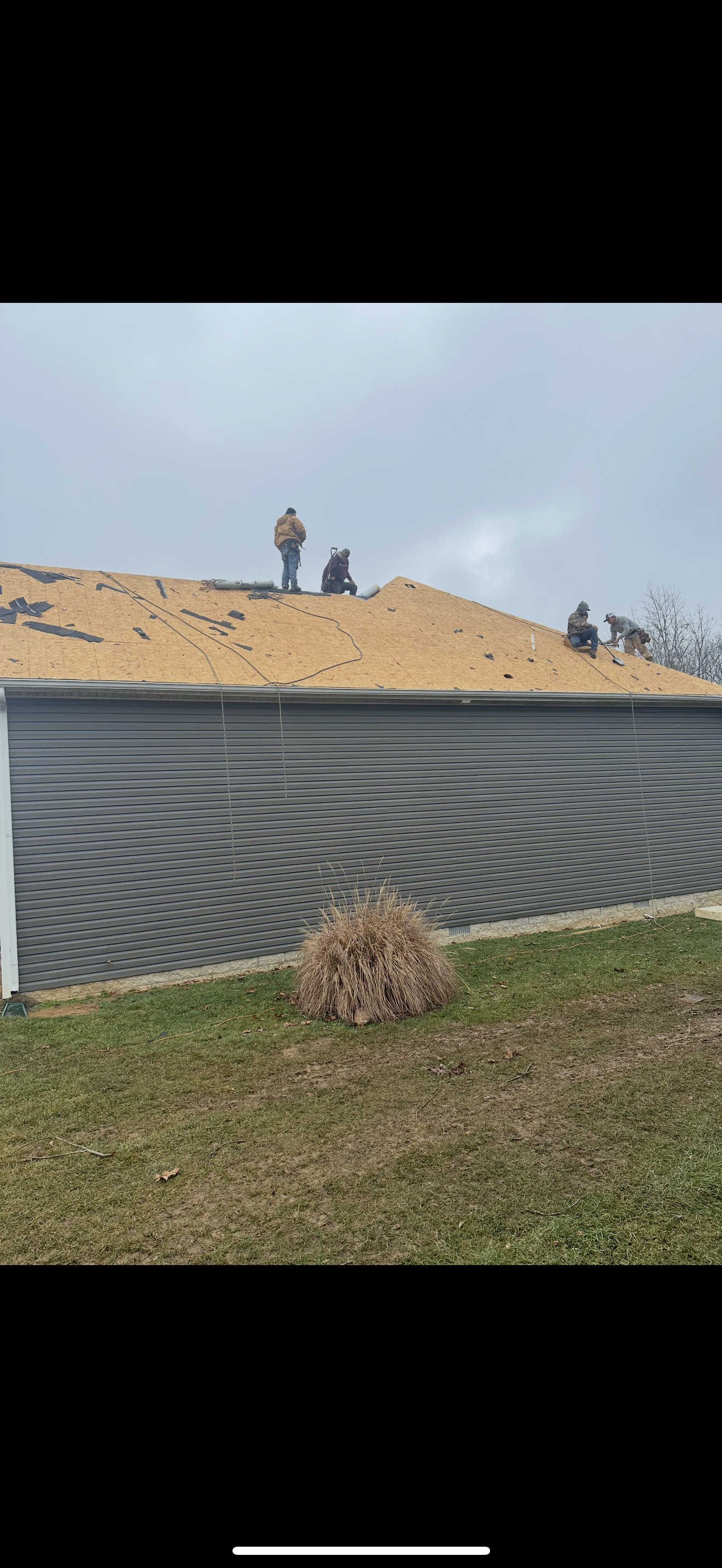 Crew tearing off shingles on gray siding home