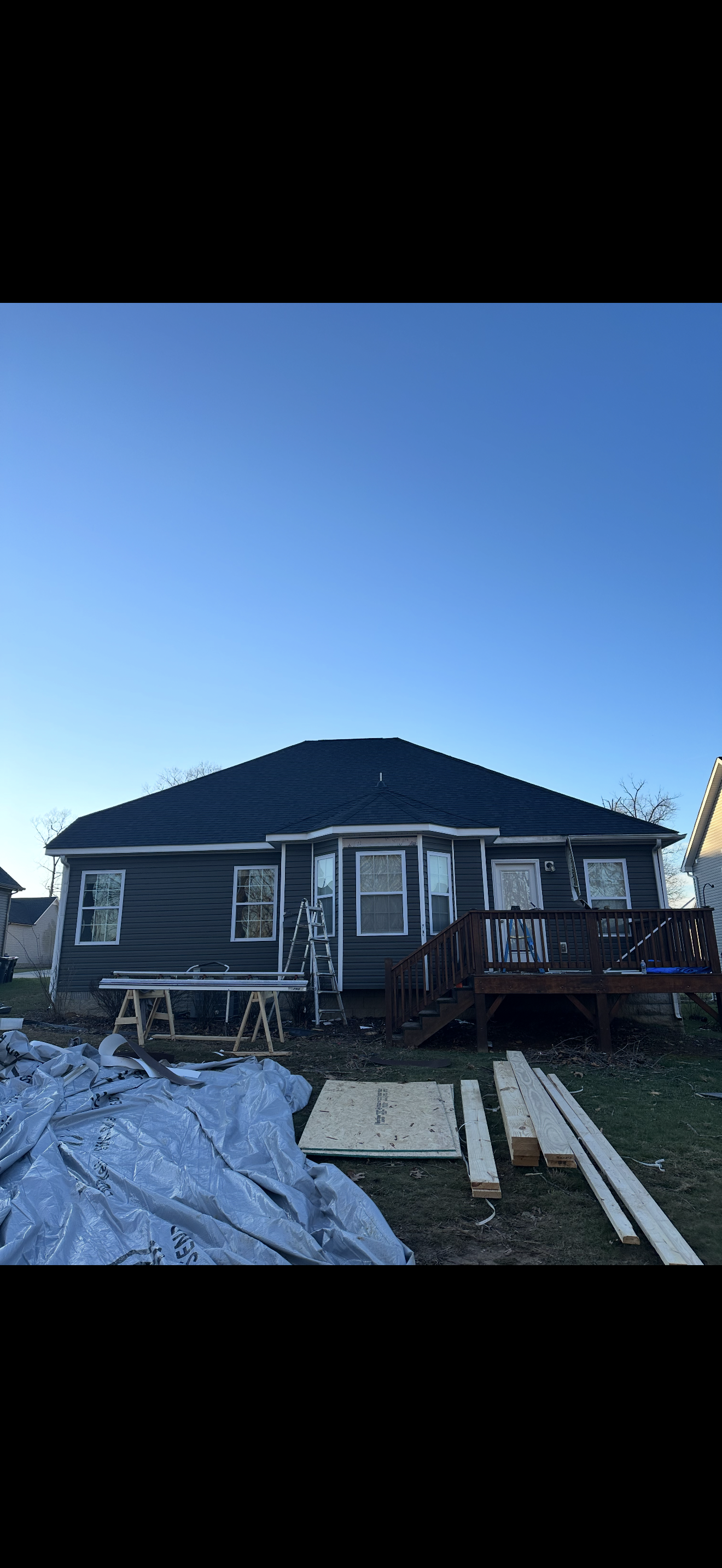 Completed roof replacement on gray home at dusk