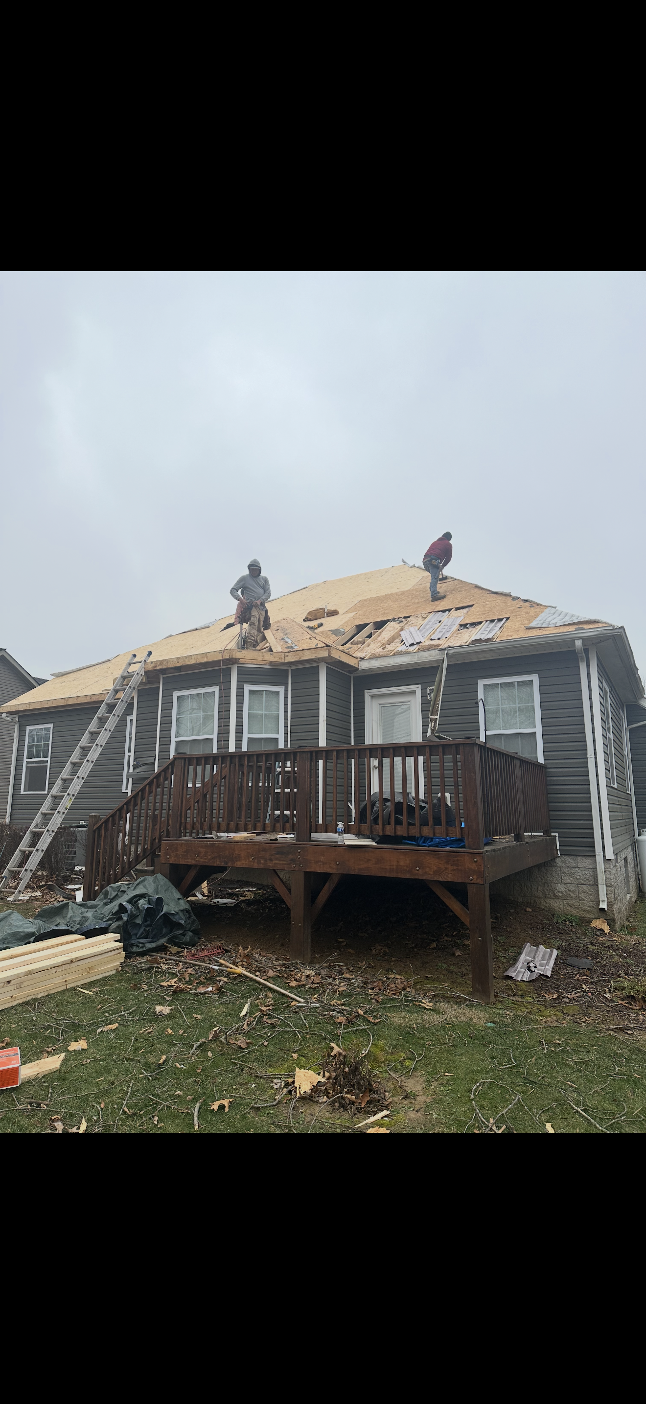 Two roofers working on exposed decking during replacement