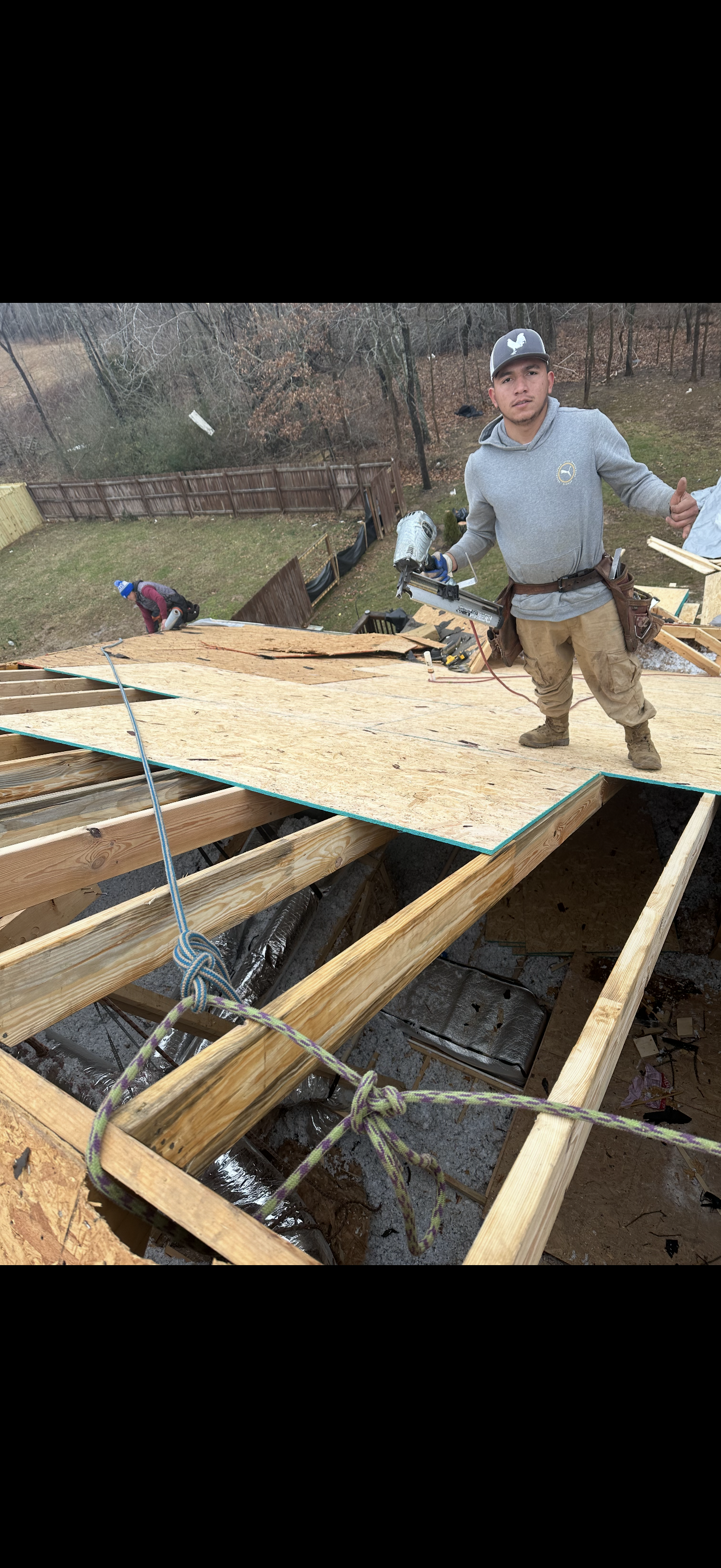 Roofer giving thumbs up while laying new OSB decking on storm-damaged home