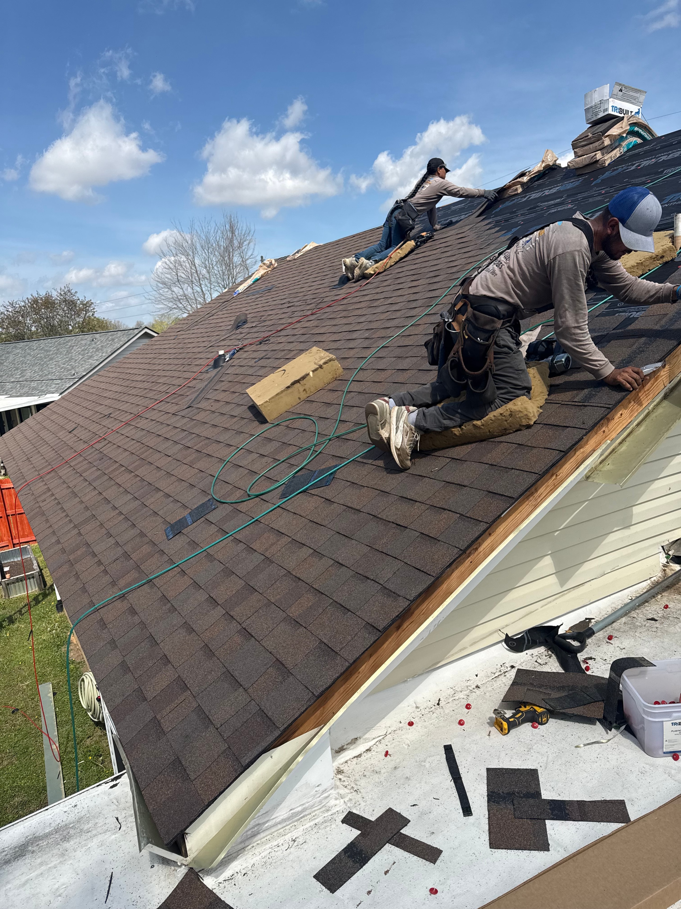 Crew laying new shingles on roof installation